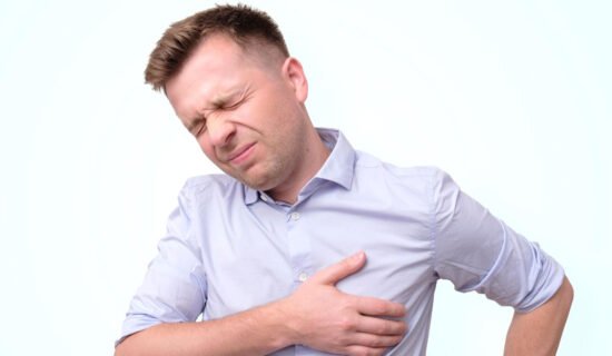 A person experiencing chest pain, clutching their chest, potentially indicating a stroke.