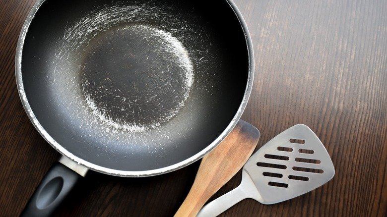 Image: Clean nonstick pan on a stovetop ALT: "Pristine nonstick pan maintained without using cooking spray" Image: Person holding an oil mister above a pan ALT: "Oil mister as a healthier alternative to cooking spray for nonstick cookware" Image: Set of wooden utensils on a countertop ALT: "Wooden cooking utensils to prevent scratching nonstick surfaces" Image: Handwashing a pan in the sink ALT: "Handwashing nonstick cookware to protect its coating and extend lifespan" Image: Cookware stacked with soft protectors between ALT: "Proper storage of nonstick pans with soft dividers to prevent damage" Imag: Pan with baking soda paste being scrubbed gently ALT: "Cleaning stubborn residue on nonstick pans using baking soda and water"