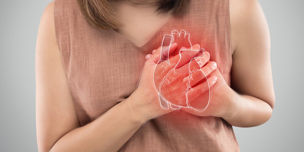 A woman holding her chest, symbolizing awareness of heart disease symptoms unique to women.
